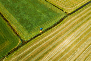 Luftaufnahme eines Traktors beim Mähen des Grases auf einem Acker in Friesland, Niederlande. - AAEF09914