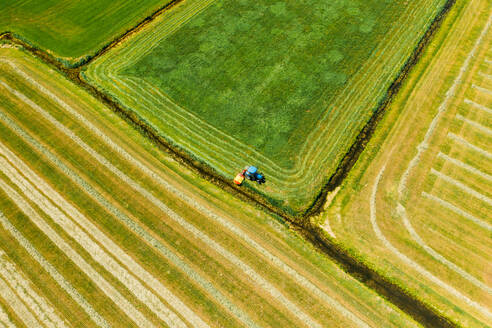Luftaufnahme eines Traktors beim Mähen des Grases auf einem Acker in Friesland, Niederlande. - AAEF09915