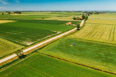 Luftaufnahme eines Traktors beim Mähen des Grases auf einem Acker in Friesland, Niederlande. - AAEF09916