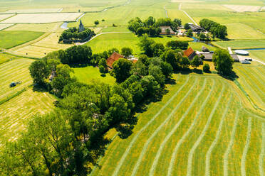 Luftaufnahme von Ackerland mit Bauernhäusern und einer Kirche in Friesland, Niederlande. - AAEF09921