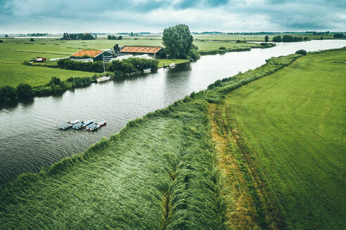 Luftaufnahme von Booten mit Solarzellen, die durch das Ackerland in Nijhuizum, Friesland, Niederlande, fahren. - AAEF09923