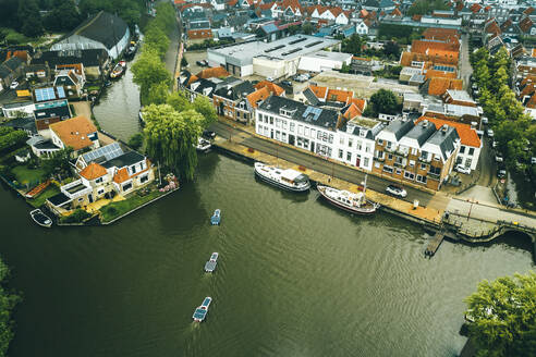 Luftaufnahme von Booten mit Solarzellen, die durch die Stadt Bolsward, Friesland, Niederlande, fahren. - AAEF09924