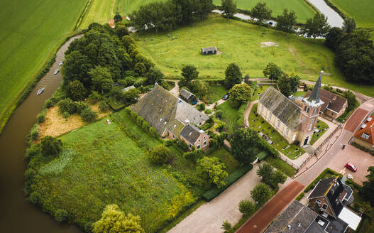 Luftaufnahme von Booten mit Solarzellen, die durch das Dorf Schettens, Friesland, Niederlande, fahren. - AAEF09927