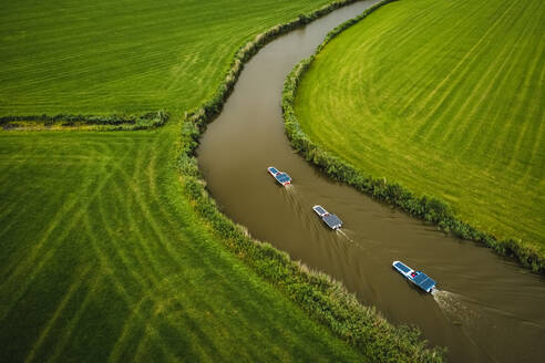 Luftaufnahme von Booten mit Solarzellen, die durch das Ackerland von Schettens, Friesland, Niederlande, fahren. - AAEF09929