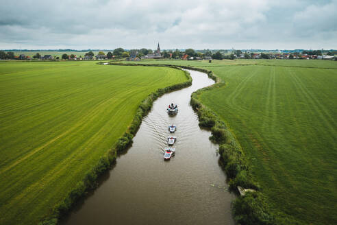 Luftaufnahme von Booten mit Solarzellen, die durch das Ackerland von Schettens, Friesland, Niederlande, fahren. - AAEF09930