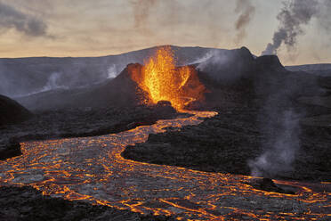 Aerial view of a volcano smoking from the crater, view of magma erupting from the crater with mountains landscape in background, Grindav√≠k, Southern Peninsula, Iceland. - AAEF09944