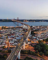 Luftaufnahme der Brücke des 25. April mit der Christkönigsstatue (Cristo Rei) im Hintergrund bei Sonnenuntergang, Blick auf die Skyline von Lissabon bei Nacht, Alc√¢ntara, Lissabon, Portugal. - AAEF09968