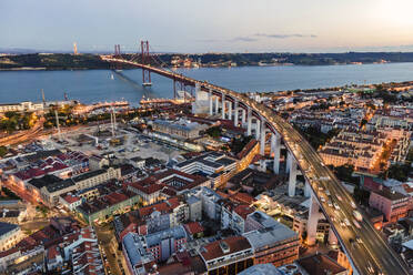 Aerial view of April 25th bridge with Christ the King statue (Cristo Rei) in background at sunset, view of Lisbon skyline at night, Alc√¢ntara, Lisbon, Portugal. - AAEF09969