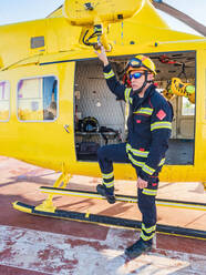 Feuerwehrmann steht neben einem gelben Hubschrauber und schaut in die Kamera - ADSF27355