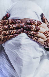 Tätowierte Hände einer nicht erkennbaren Frau bedecken die Augen einer anonymen arabischen Person mit traditionellem weißen Kopftuch - ADSF27406