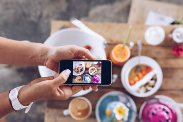 Crop hand taking photo to desserts and cups on wooden table - ADSF27471