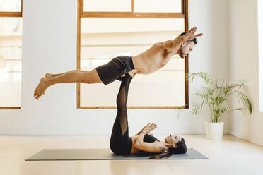 Liegend auf Yogamatte junge Frau hält muskulösen Mann auf Heben Beine auf Lektion in der Ausbildung Zimmer - ADSF27494