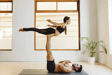 Paar, das in einer Yoga-Sitzung im Schulungsraum eine Gleichgewichtshaltung einnimmt - ADSF27496