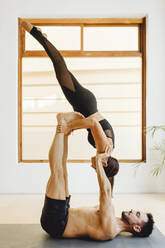 Couple making a balance position in a yoga session in training room - ADSF27497