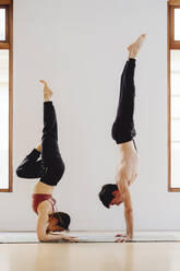 Couple making a balance position in a yoga session in training room - ADSF27505