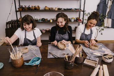 Frauen arbeiten mit Holzwerkzeugen an der Herstellung von Ornamenten aus Ton - ADSF27562