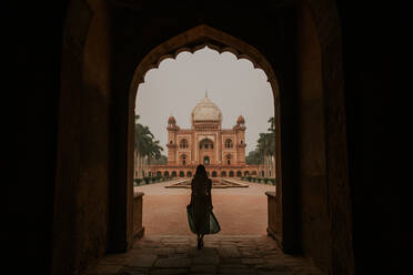 Full body back view silhouette of anonymous female tourist admiring historic building of Safdarjungs Tomb in New Delhi - ADSF27602