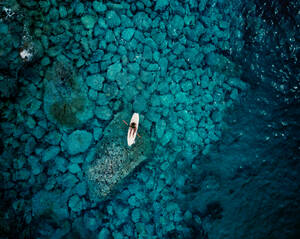 Aerial view of a person in kayak surrounded by crystalline waters in Caminia, Calabria, Italy. - AAEF10037