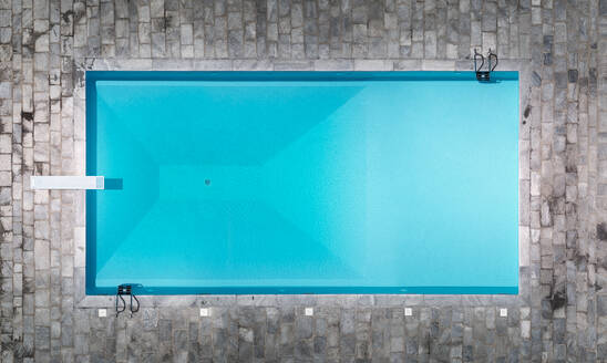 Luftaufnahme des schönen Swimmingpools eines Resorts mit Sprungbrett und türkisfarbenem Wasser in Monticello, Lombardei, Italien. - AAEF10049