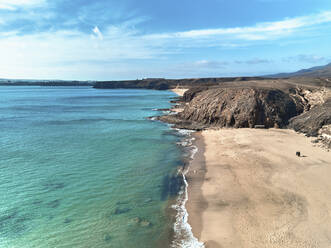 Luftaufnahme eines schönen Strandes mit einem Paar, das im Sand spazieren geht, in Playa del Pozo, Lanzarote, Spanien. - AAEF10056