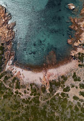 Luftaufnahme eines schönen und abgelegenen kleinen Strandes, umgeben von rötlichen Klippen und einem türkisfarbenen, transparenten Meer in Isola Rossa, Sardinien, Italien. - AAEF10057