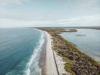 Aerial view of three small people walking on a beach with water on two sides, Bribie Island, Queensland, Australia. - AAEF10080