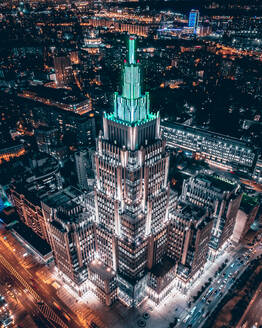 Luftaufnahme der Beleuchtung des Geschäftszentrums Oruzheyniy, das wie eine antike Ziggurat inmitten der nächtlichen Lichter der Stadt aussieht, Moskau, Russland - AAEF10155