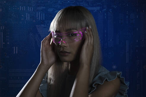 Frau mit futuristischer rosa Brille vor blauem Hintergrund - EIF01758