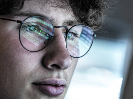 Teenage boy with eyeglasses checking stock data online at home - ABRF00907