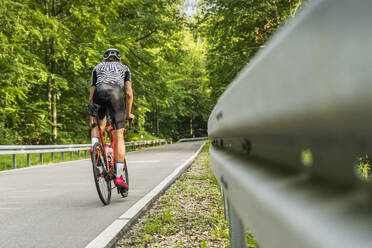 Sportler fährt Fahrrad auf einer Straße im Wald - STSF03008