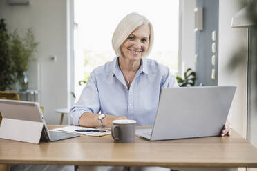 Smiling female professional working at home office - UUF24007
