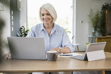 Reife Geschäftsfrau arbeitet am Laptop im Büro zu Hause - UUF24009