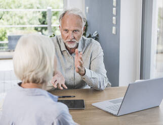 Businessman gesturing while discussing with female colleague at home office - UUF24024