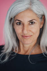 Mature female professional with white hair against pink background - JOSEF05042