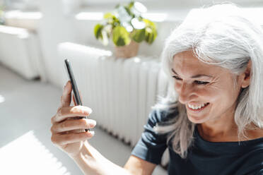 Lächelnde Geschäftsfrau nimmt Selfie durch Handy im Büro - JOSEF05055