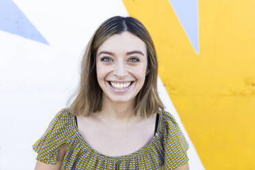 Young woman smiling in front of wall - DAMF00841