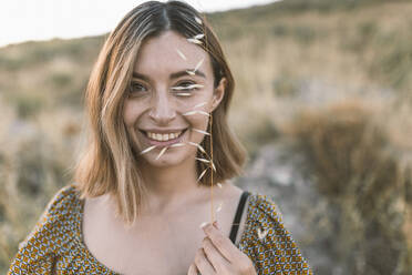 Woman smiling while holding plant in field - DAMF00844