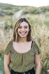 Young woman smiling while standing in field - DAMF00861