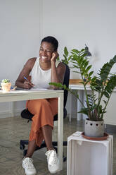 Businesswoman laughing while working at desk - VEGF04706