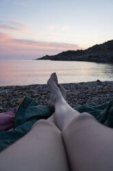 Frau mit überkreuzten Beinen am Strand entspannt - AFVF09032