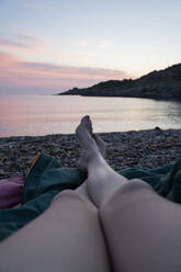 Woman with legs crossed at ankle relaxing at beach - AFVF09032