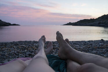 Mid adult couple relaxing with legs crossed at ankle during sunrise - AFVF09033