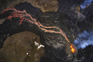 Luftaufnahme eines aus dem Krater rauchenden Vulkans, Blick auf aus dem Krater ausbrechendes Magma mit Berglandschaft im Hintergrund, Grindav√≠k, Südliche Halbinsel, Island. - AAEF10335