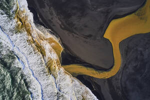 Luftaufnahme einer farbenfrohen Flussmündung entlang der Küstenlinie mit Blick auf den Ozean, Rang√°rbing eystra, Südisland. - AAEF10359