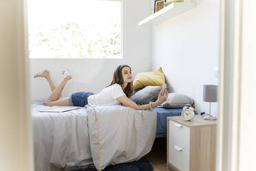 Woman taking selfie through smart phone while lying on bed at home - JCCMF03269