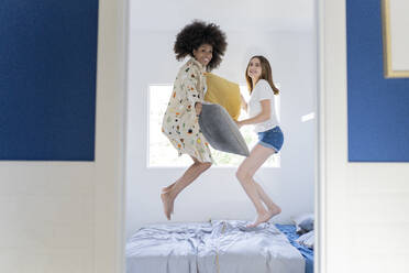 Multiethnische Freundinnen springen zu Hause auf dem Bett herum - JCCMF03271