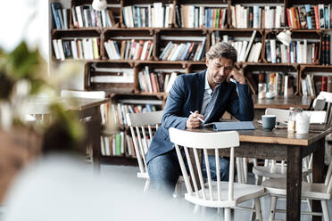 Reifer Geschäftsmann bei der Arbeit mit einem digitalen Tablet am Tisch im Café sitzend - JOSEF05090