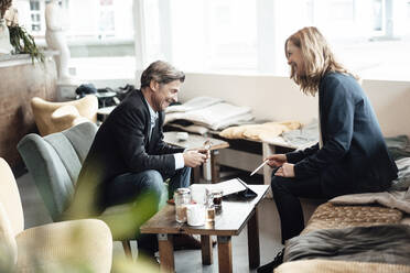 Glücklicher Geschäftsmann und Geschäftsfrau lachen, während sie zusammen in einem Café diskutieren - JOSEF05105