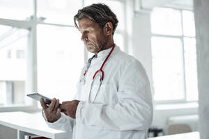 Männlicher Angestellter des Gesundheitswesens benutzt ein digitales Tablet in einer medizinischen Klinik - JOSEF05137