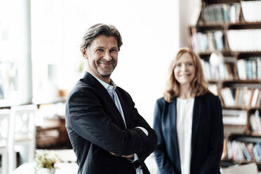 Smiling mature male professional standing with arms crossed in cafe - JOSEF05166